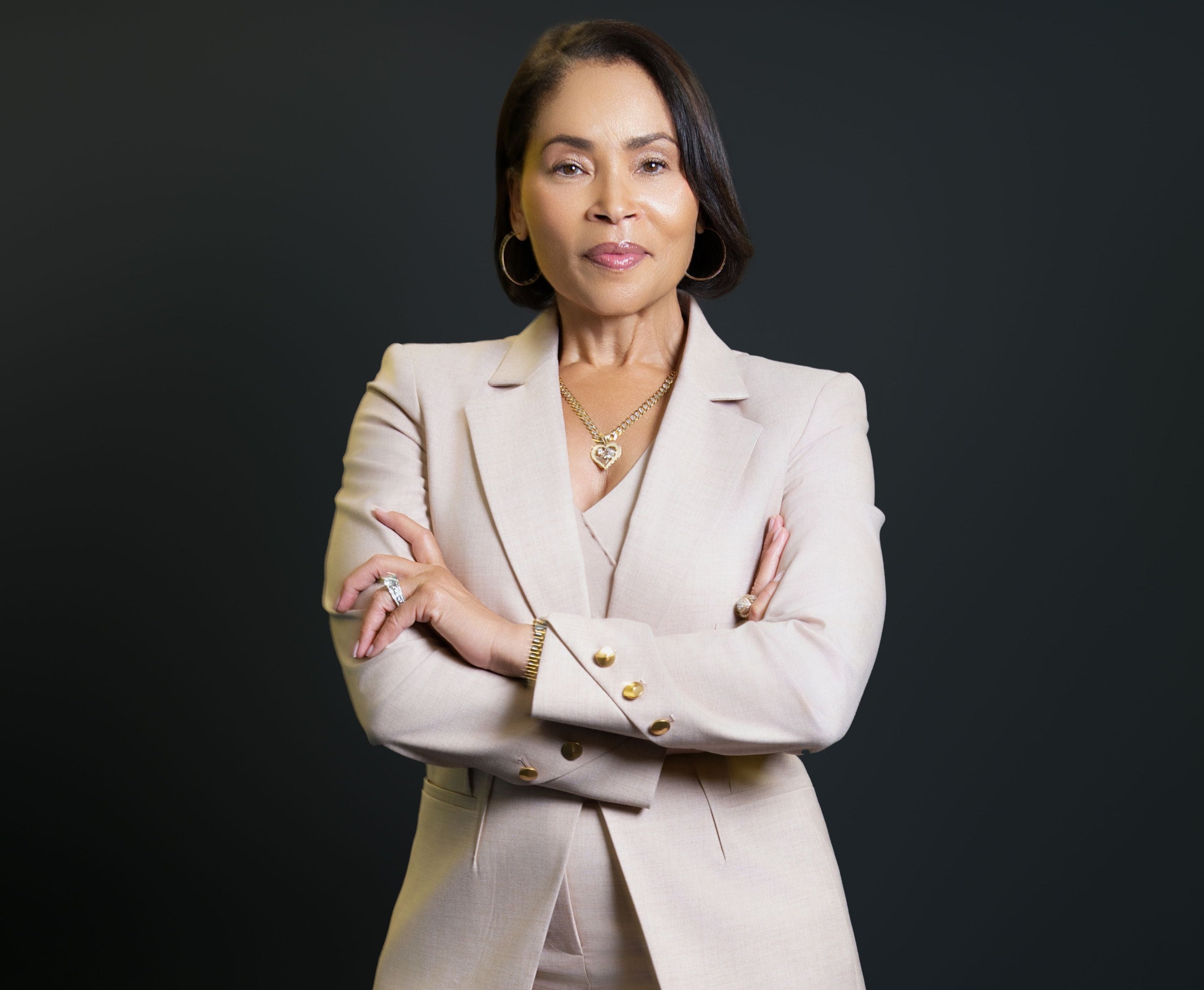 Woman in a beige suit standing against a black background
